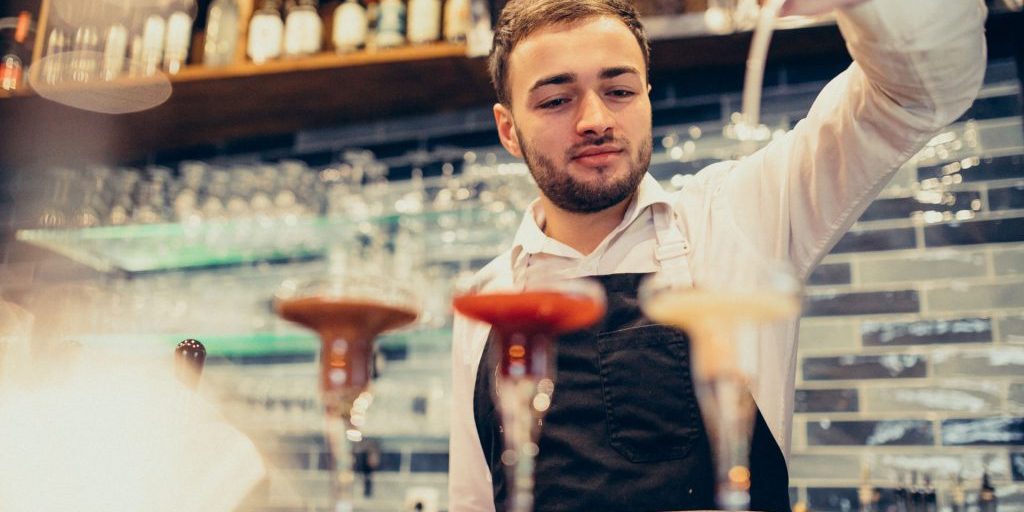 Handsome bartender making drinking and cocktails at a counter