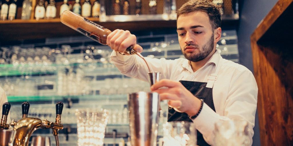 Handsome bartender making drinking and cocktails at a counter